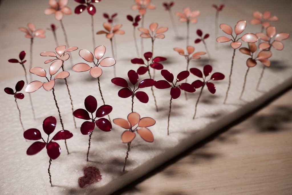 Lots of nail polish flowers in shades of pink made from wire and nail polish