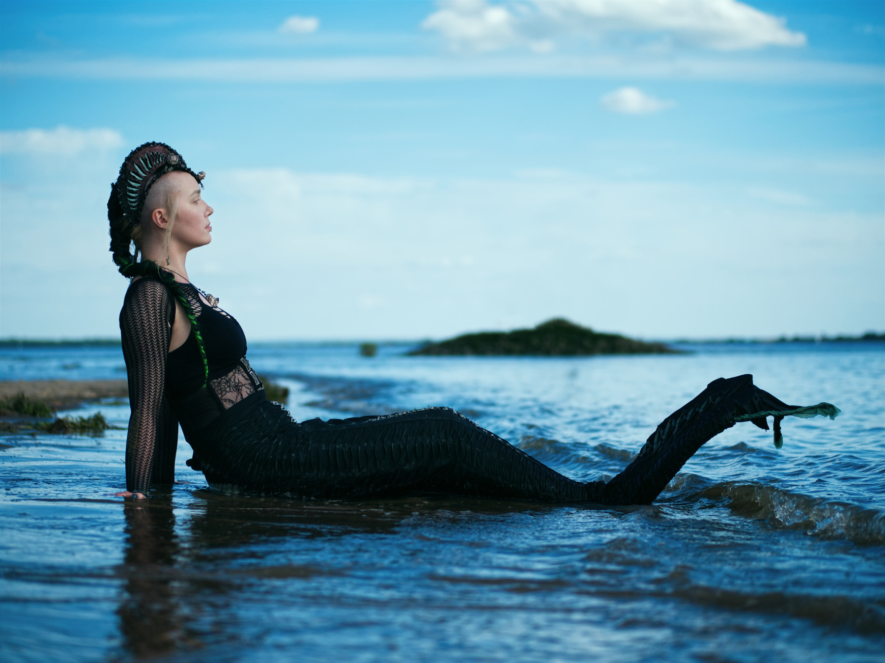 Meerjungfrau Miruna sitzt am Strand und schaut aufs Meer