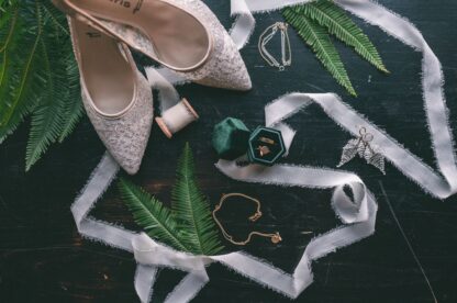 Flatlay für eine Hochzeit bestehend aus Brautschuhen, Eheringen, einer Kette und einem Paar Ohrringen von Faunauge